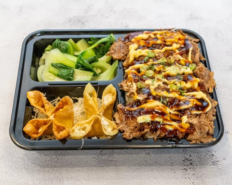 Takeout container with shredded beef, bok choy, and crab rangoons on a white background.